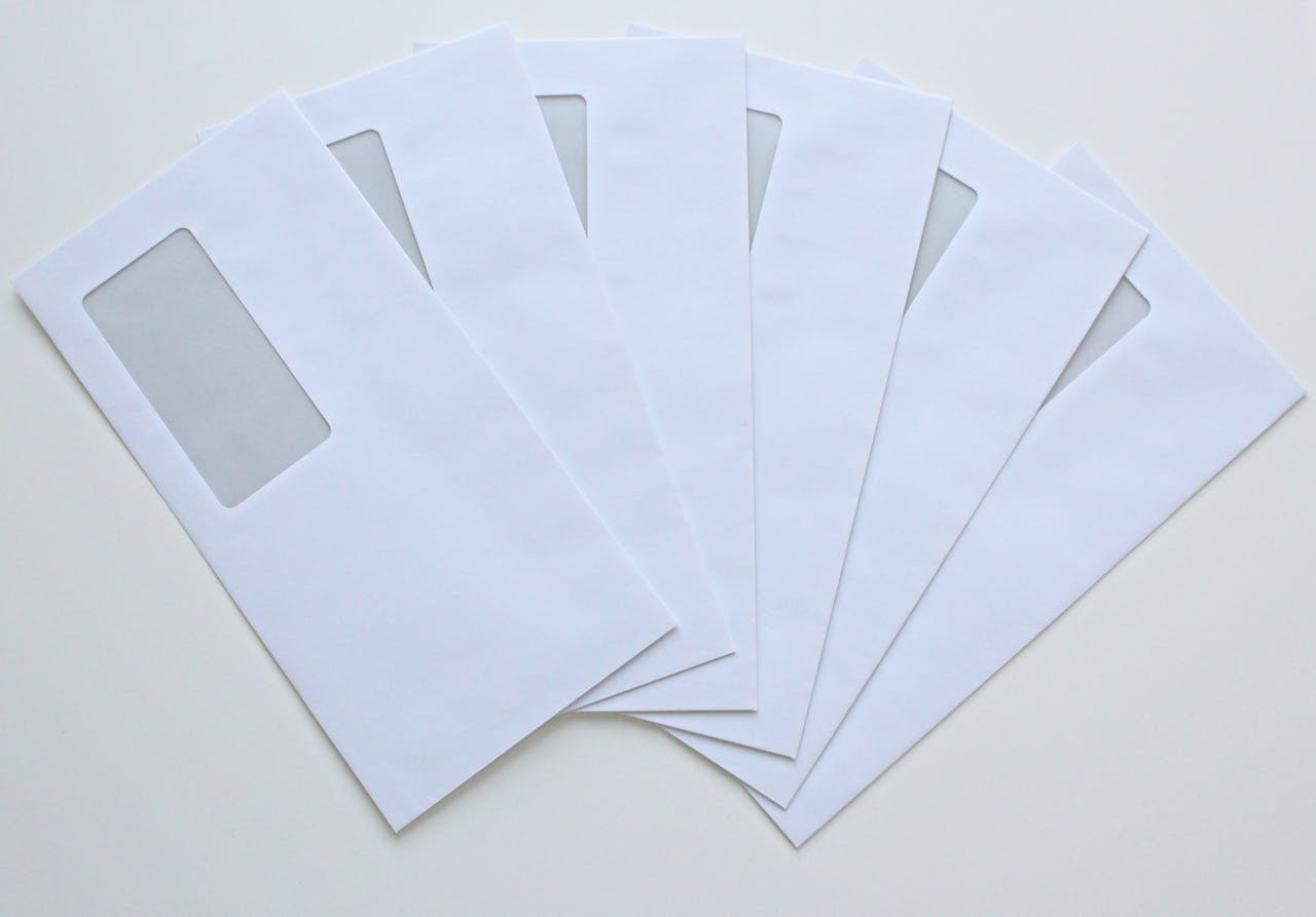 A set of white window envelopes fanned out on a flat surface, ready for mailing or office use.